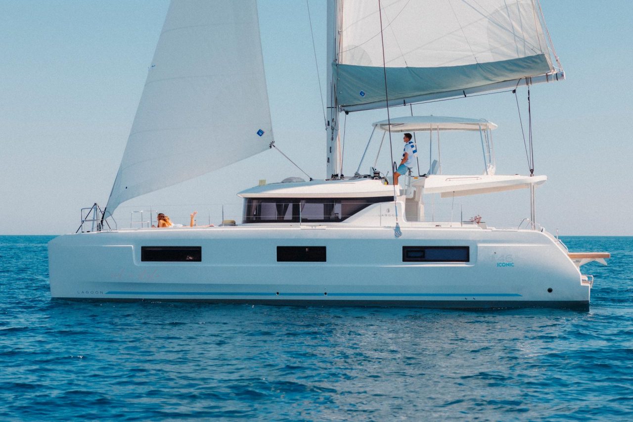 Lagoon 46 Iconic sailing with a man at the helm and women enjoying the foredeck