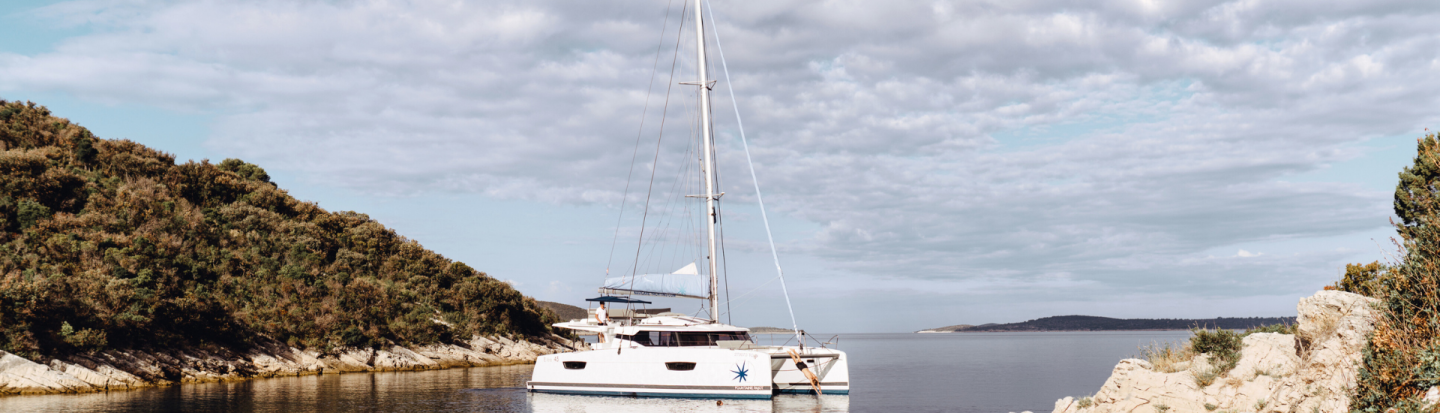 A man diving from an anchored sailing catamaran