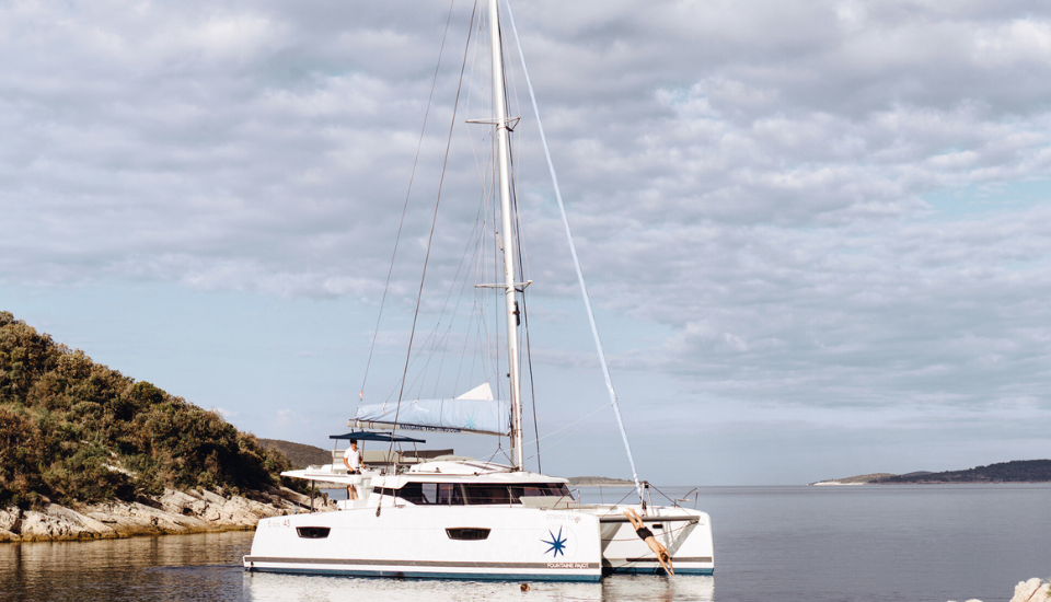 A man diving from an anchored sailing catamaran