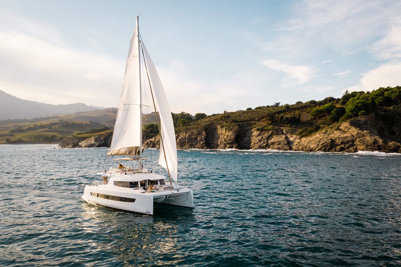 Bali 4.6 sailing with a woman at the helm and guests enjoying the foredeck