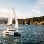 Bali 4.6 sailing with a woman at the helm and guests enjoying the foredeck