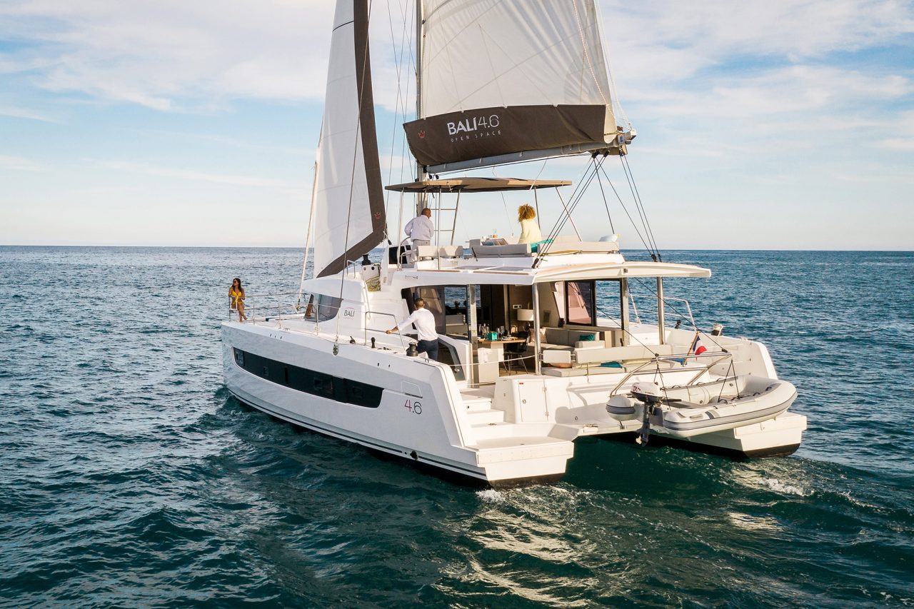 Bali 4.6 sailing with a man at the helm and guests enjoying the foredeck and the flybridge