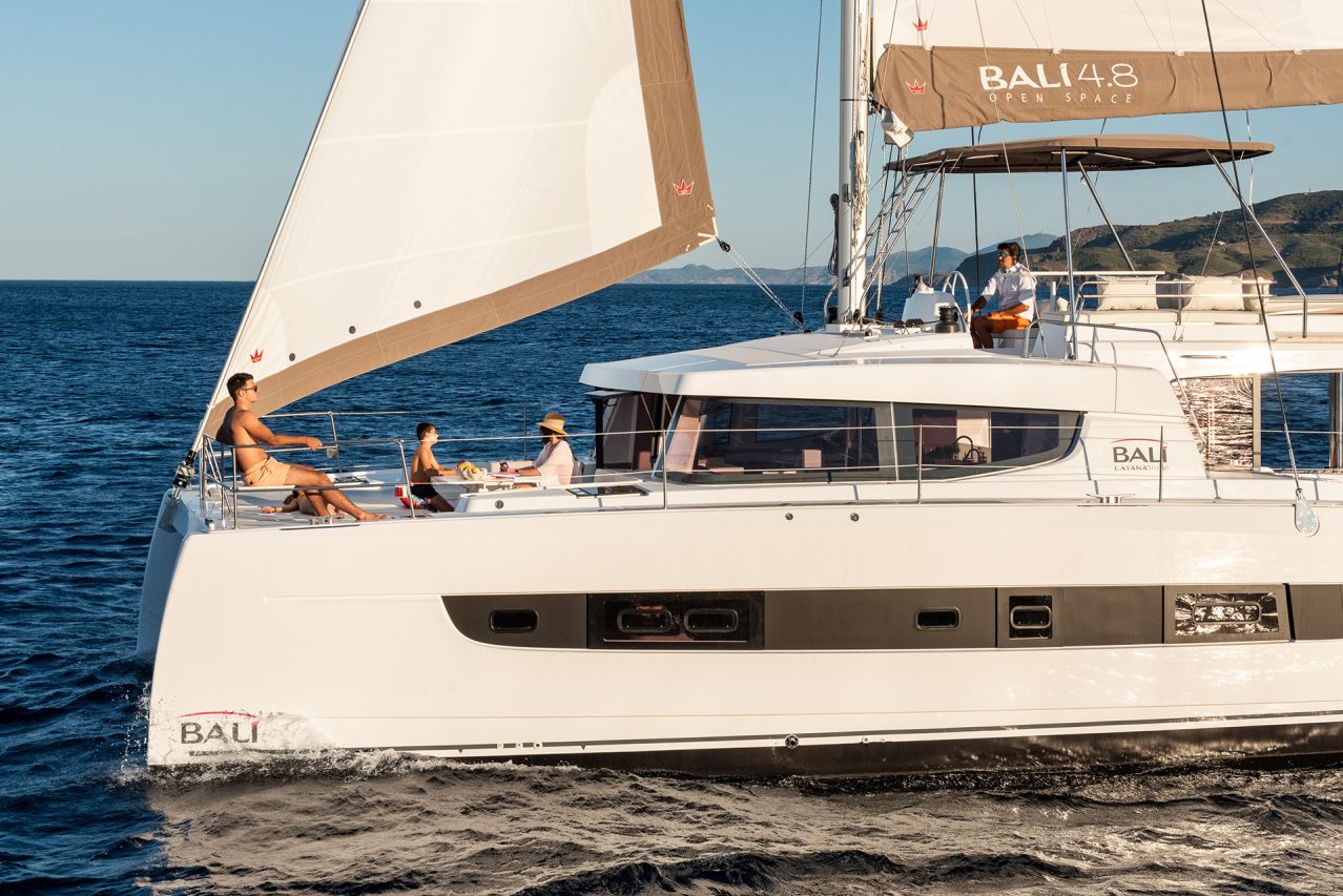 Bali 4.8 sailing with a man at the helm and guests enjoying the foredeck