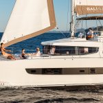 Bali 4.8 sailing with a man at the helm and guests enjoying the foredeck