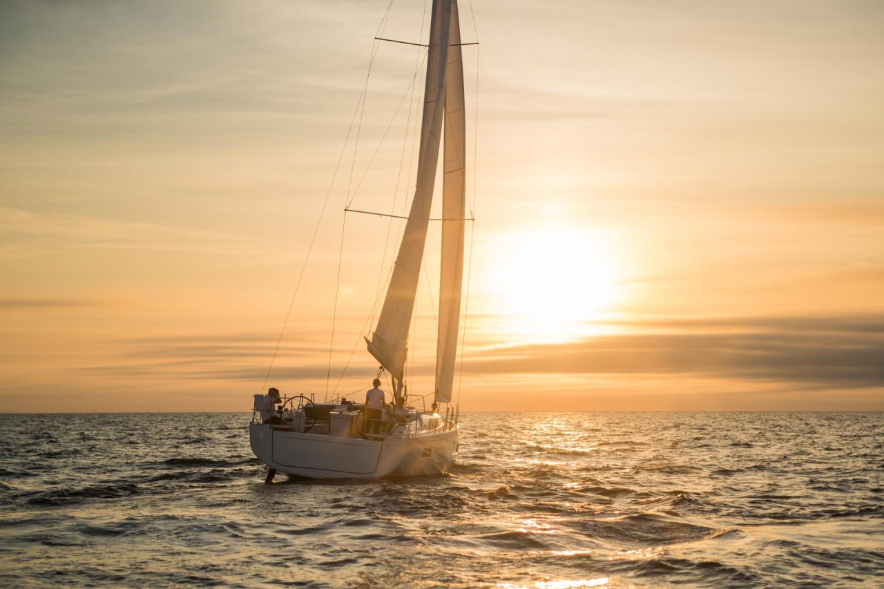Beneteau Oceanis 40.1 sailing with a women at the helm at sunset