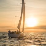 Beneteau Oceanis 40.1 sailing with a women at the helm at sunset