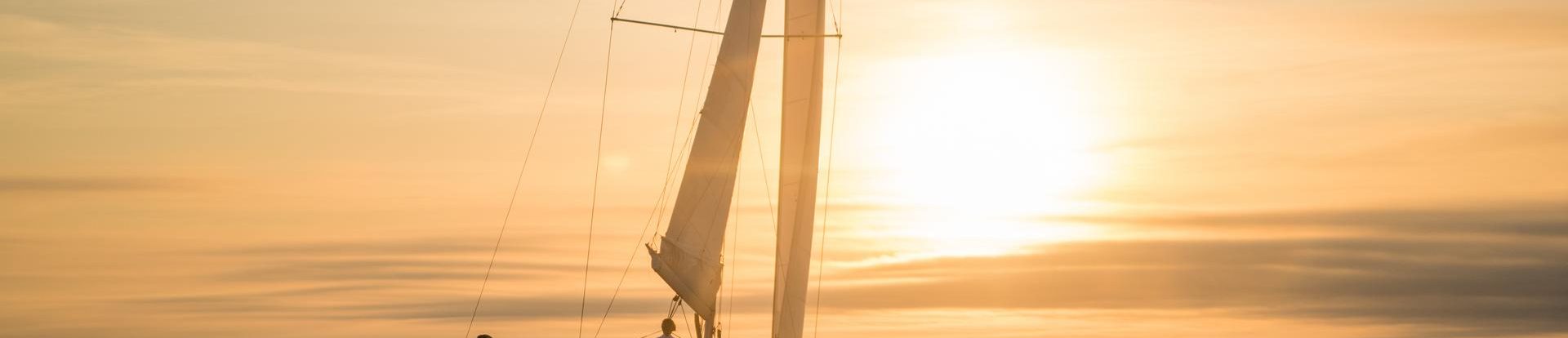 Beneteau Oceanis 40.1 beim Segeln mit einer Frau am Ruder bei Sonnenuntergang