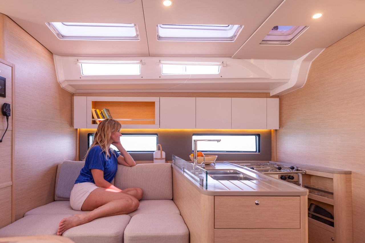 Woman sitting just next to the smart and fully equiped galley aboard the Dufour 48 sailing monohull