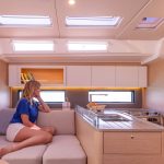 Woman sitting just next to the smart and fully equiped galley aboard the Dufour 48 sailing monohull
