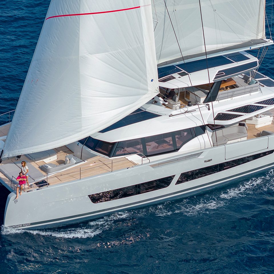 Rear view of the Fountaine Pajot Thira 80 sailing with a couple on the foredeck