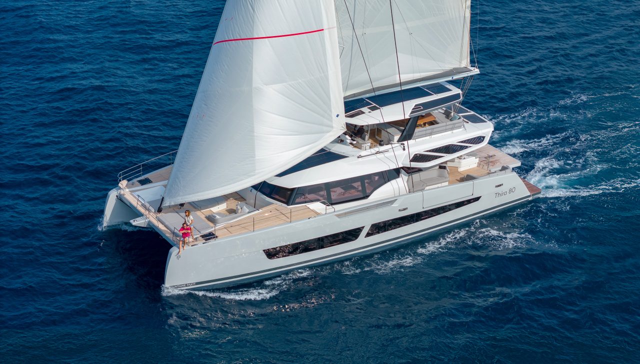 Rear view of the Fountaine Pajot Thira 80 sailing with a couple on the foredeck