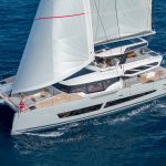 Rear view of the Fountaine Pajot Thira 80 sailing with a couple on the foredeck