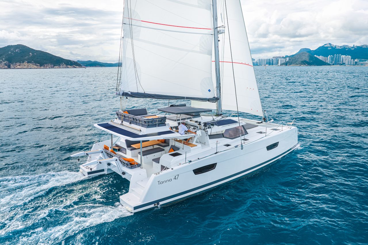 Fountaine Pajot Tanna 47 sailing near the coast with a man at the helm