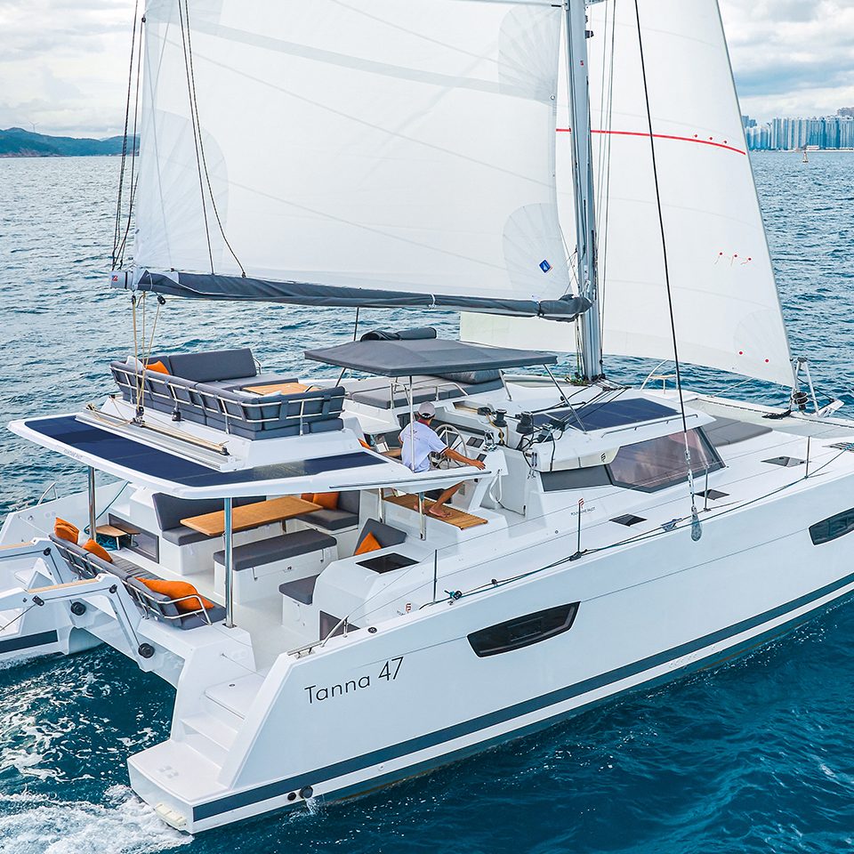 Fountaine Pajot Tanna 47 sailing near the coast with a man at the helm