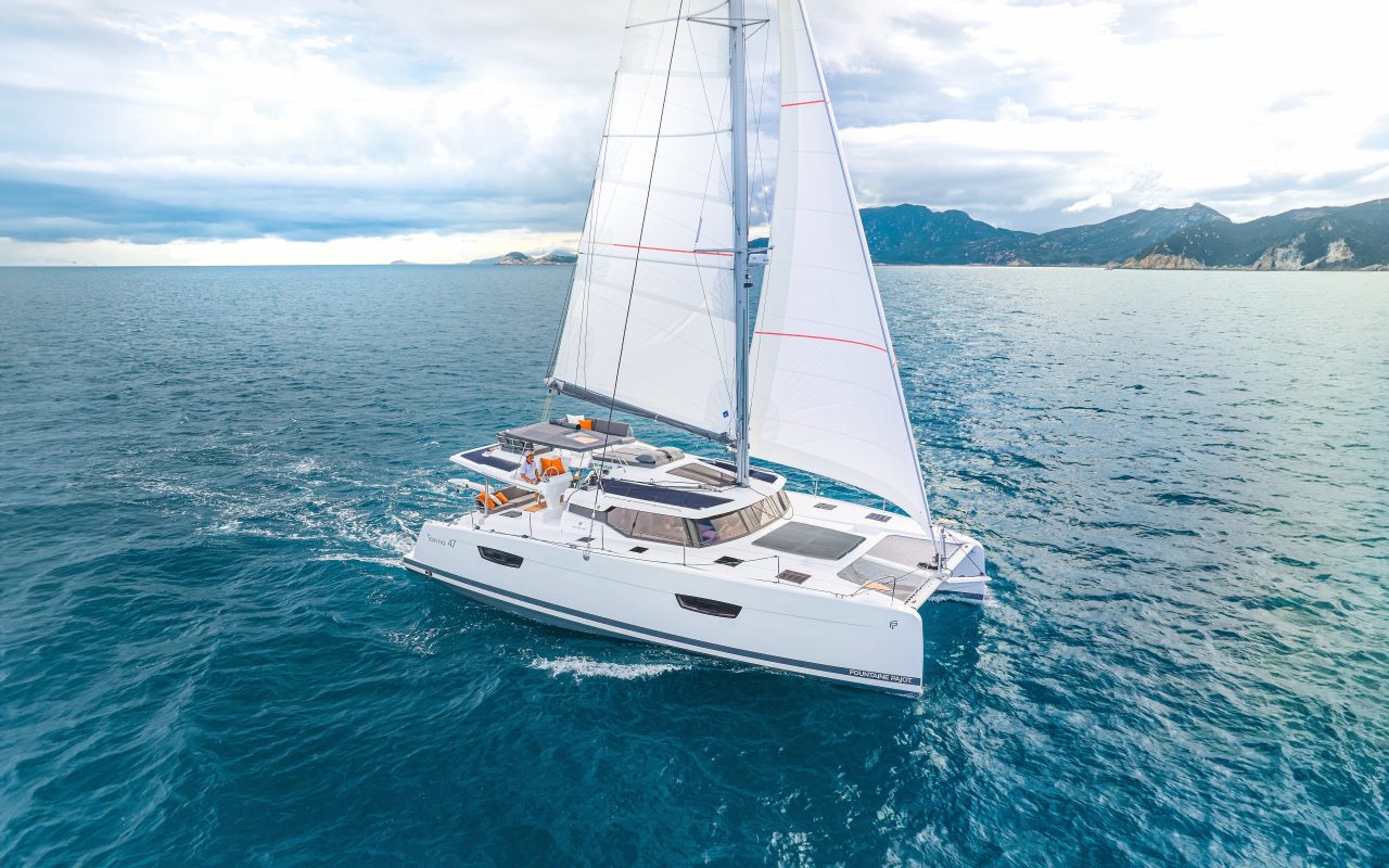Fountaine Pajot Tanna 47 sailing near the coast with a man at the helm
