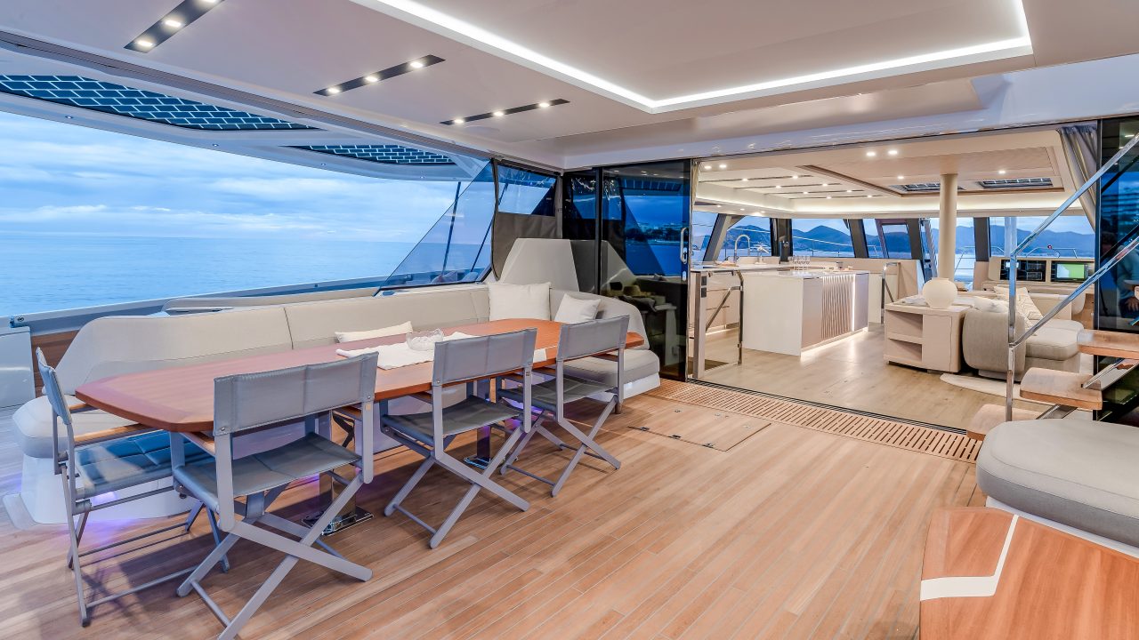 Mujeres sentadas en el banco lateral de cubierta del catamarán de vela Fountaine Pajot Thira 80.