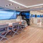 Mujeres sentadas en el banco lateral de cubierta del catamarán de vela Fountaine Pajot Thira 80.