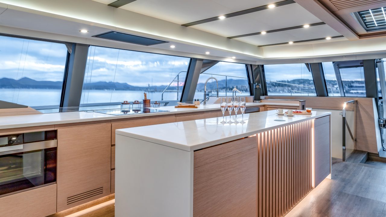 Hombres en el sofisticado puesto de mando del catamarán a vela Fountaine Pajot Thira 80