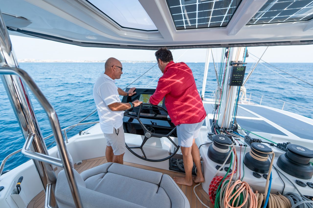 Hombres en el sofisticado puesto de mando del catamarán a vela Fountaine Pajot Thira 80