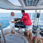 Hombres en el sofisticado puesto de mando del catamarán a vela Fountaine Pajot Thira 80