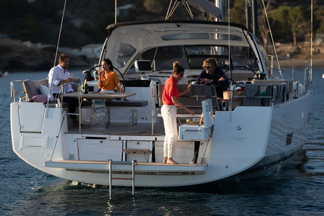 Rear view of the Jeanneau 55 at anchor with guests having a barbecue in the cockpit