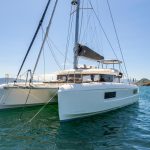 Front view of the Lagoon 43 sailing catamaran at anchor with guests enjoying the flybridge