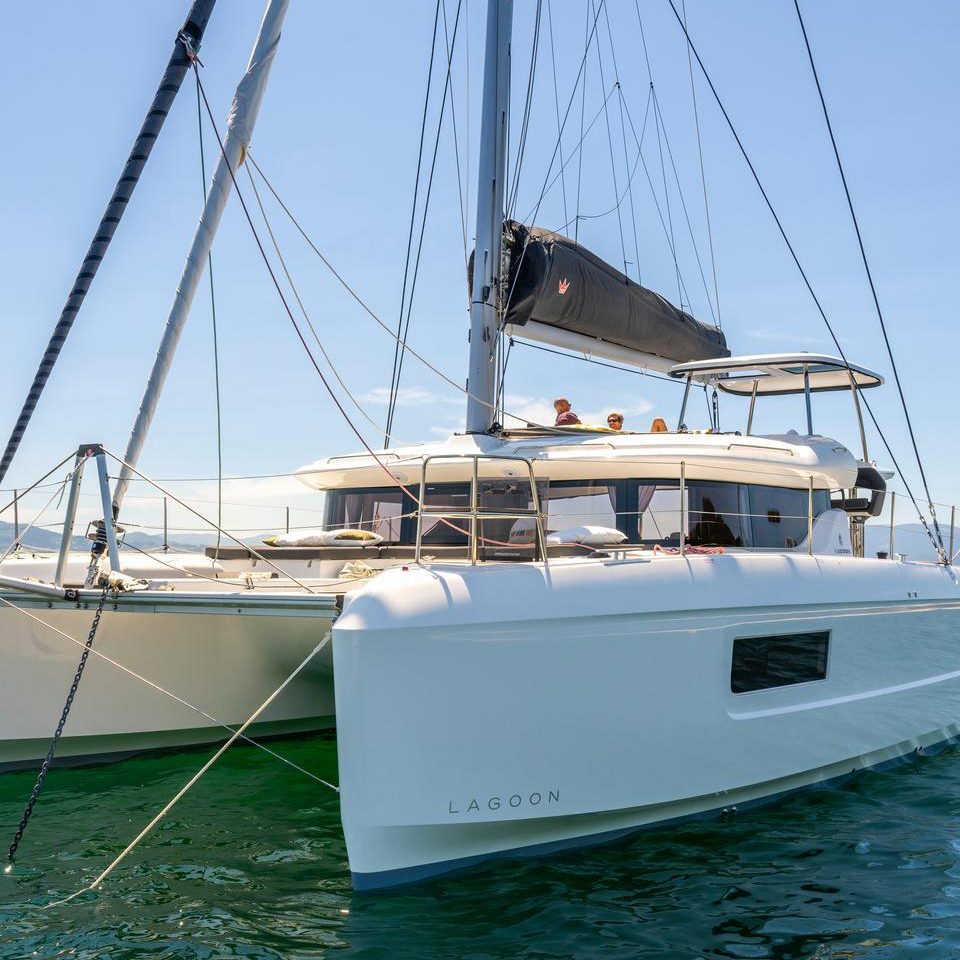 Front view of the Lagoon 43 sailing catamaran at anchor with guests enjoying the flybridge