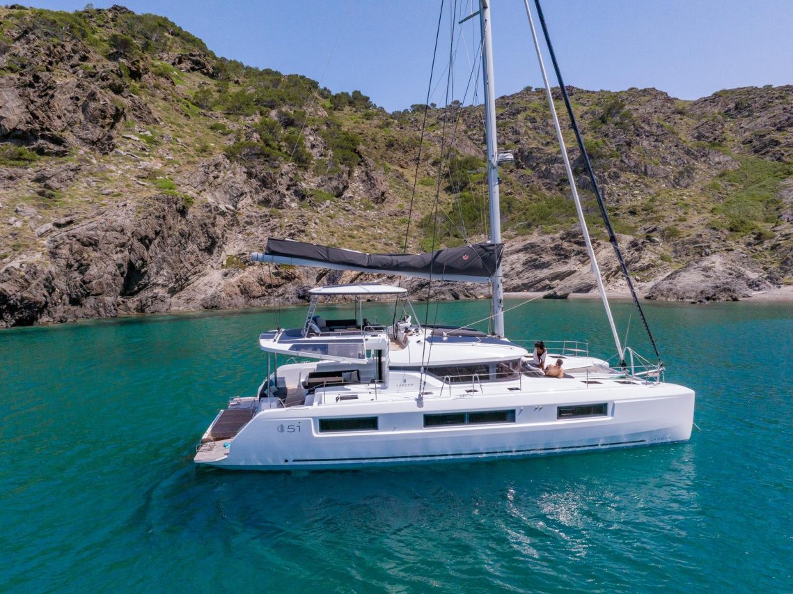 Lagoon 51 vor Anker in türkisfarbenem Wasser mit Gästen auf dem Vordeck