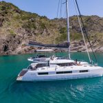 Lagoon 51 vor Anker in türkisfarbenem Wasser mit Gästen auf dem Vordeck