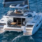 Guests enjoying the cockpit of the Lagoon 51 sailing catamaran with a man at the helm
