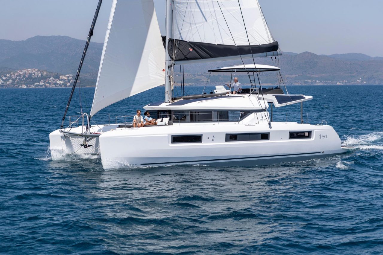 Lagoon 51 sailing with a man at the helm and guests enjoying the foredeck