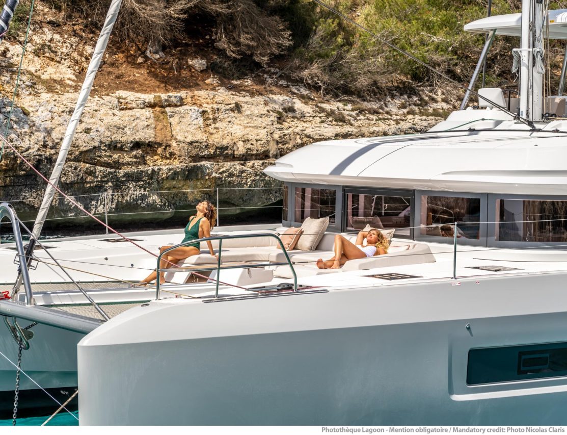 Women taking sun on the comfortable foredeck of the Lagoon 55 sailing catamaran