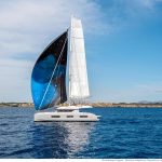 Lagoon 55 sailing with a man at the helm and women enjoying the flybridge and the cockpit