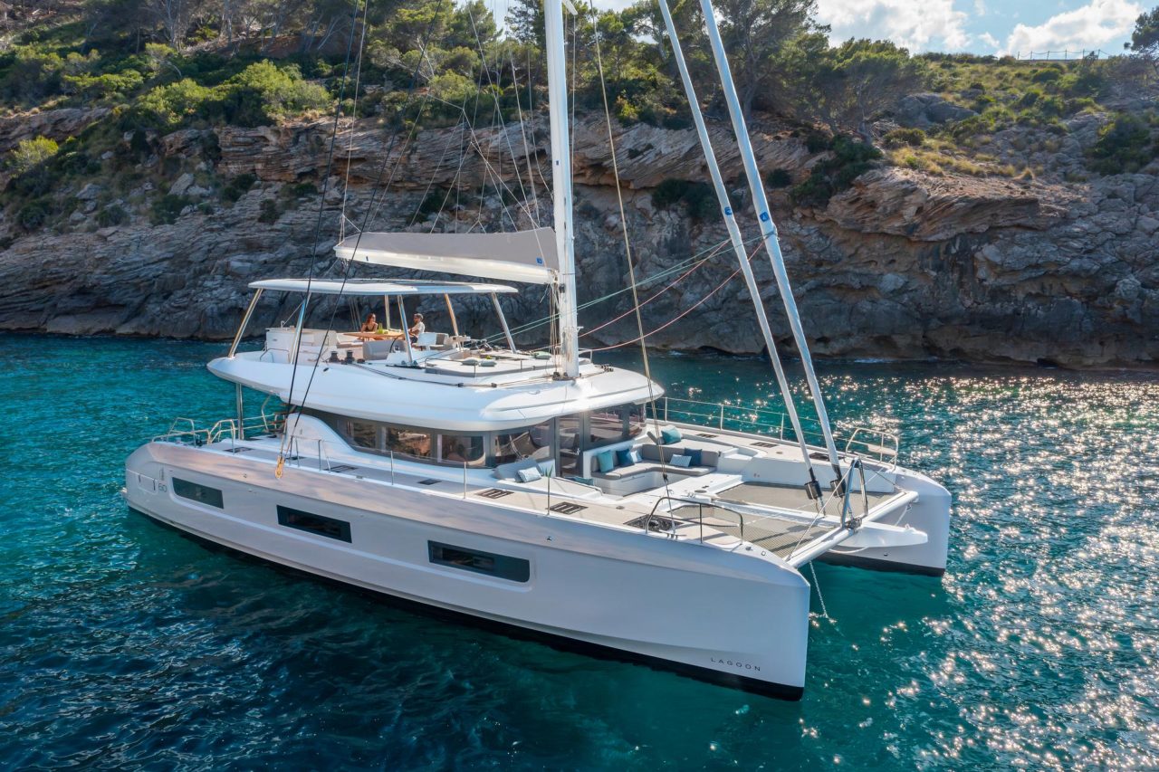Lagoon 55 sailing catamaran at anchor with guests enjoying the flybridge