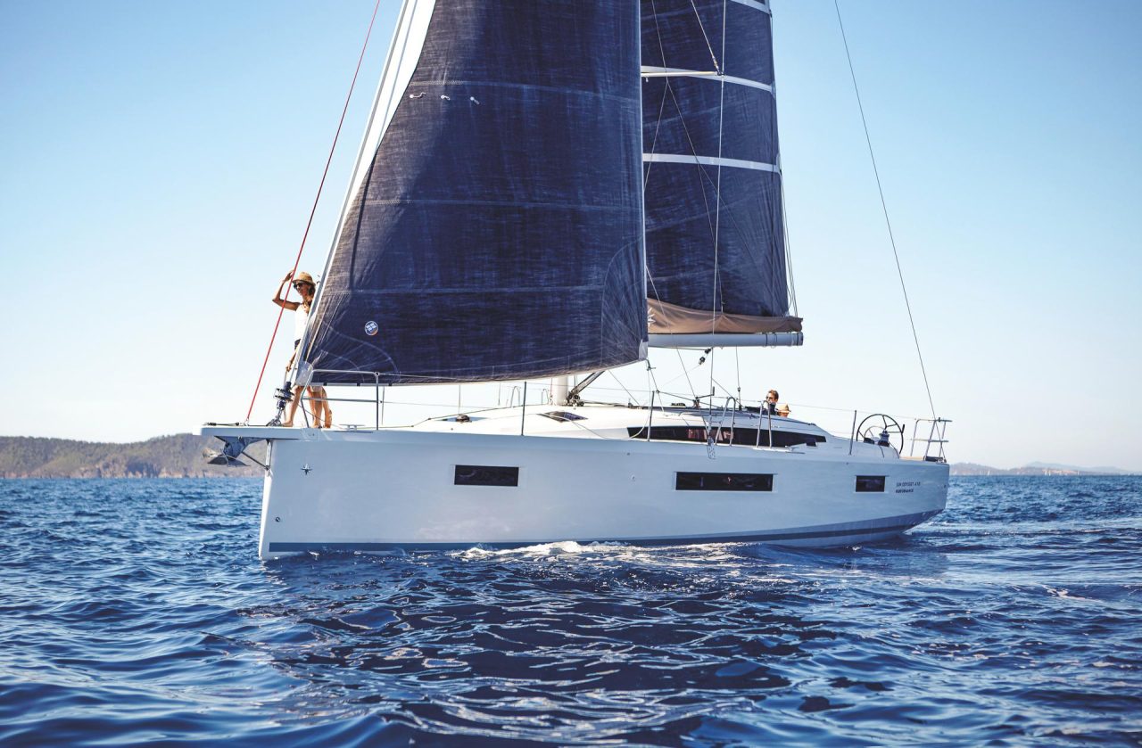 Jeanneau Sun Odyssey 410 sailing with a man at the helm and a woman enjoying the foredeck