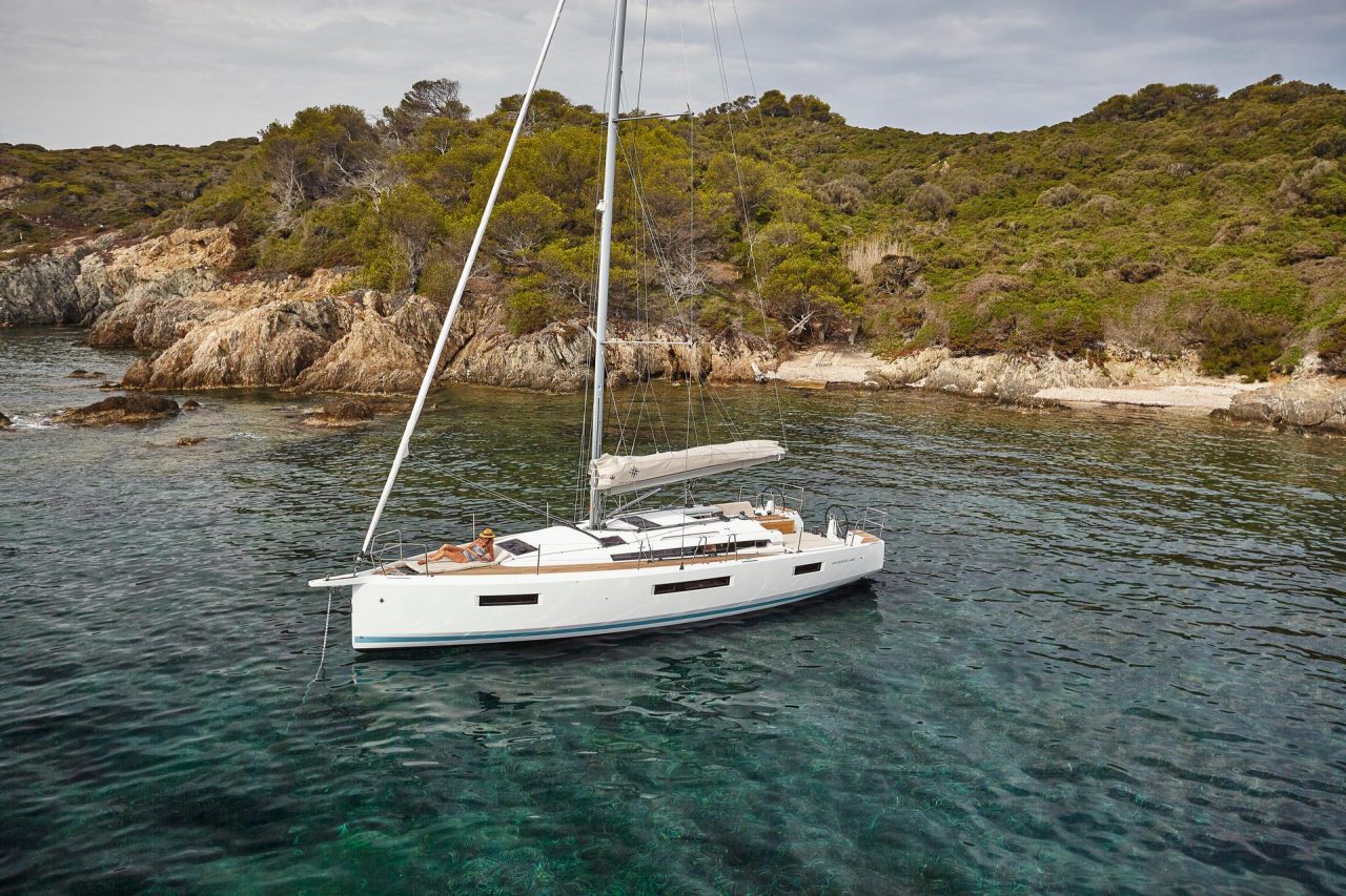 Aerial view of the Jeanneau Sun Odyssey 440 sailing monohull at anchor with a woman and a man enjoying foredeck