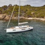 Aerial view of the Jeanneau Sun Odyssey 440 sailing monohull at anchor with a woman and a man enjoying foredeck