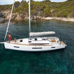 Aerial view of the Jeanneau Sun Odyssey 440 sailing monohull at anchor with a woman and a man enjoying foredeck