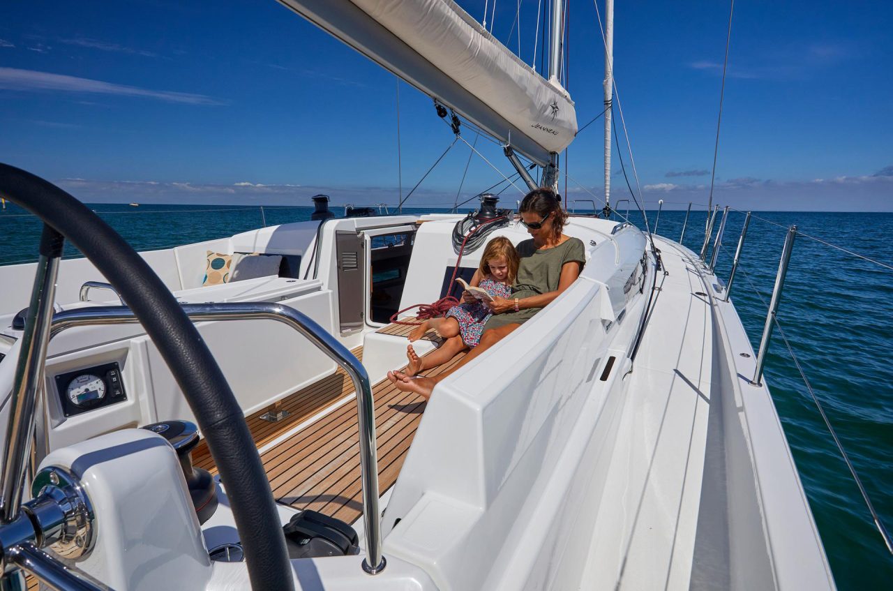 Mother reading a book with her daugther on the Jeanneau Sun Odyssey 490 cockpit