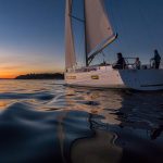 Jeanneau Sun Odyssey 490 sailing near the coast at sunset
