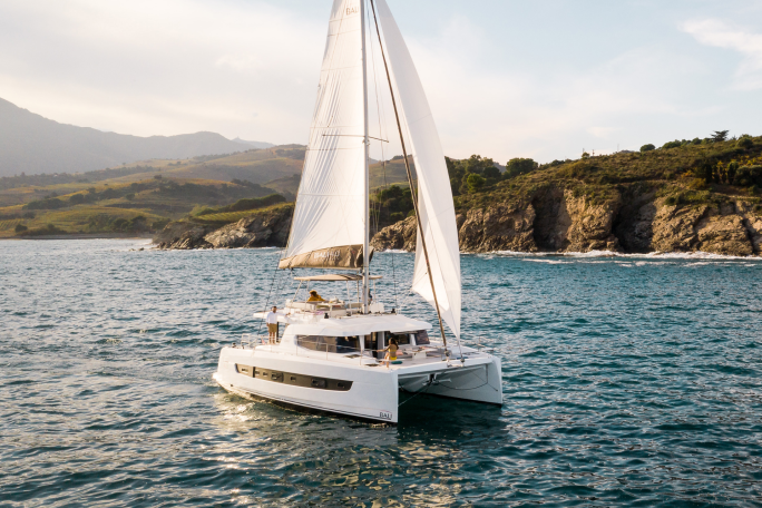 Bali 4.6 sailing with a woman at the helm and guests enjoying the foredeck