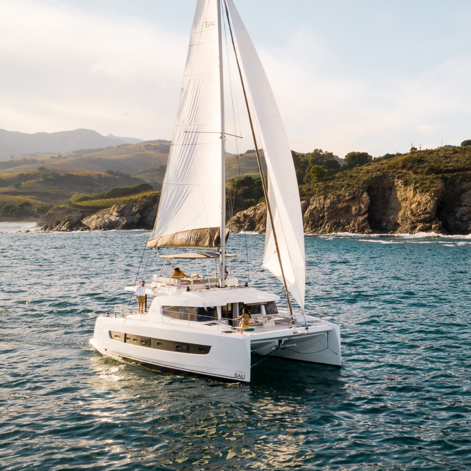 Bali 4.6 sailing with a woman at the helm and guests enjoying the foredeck