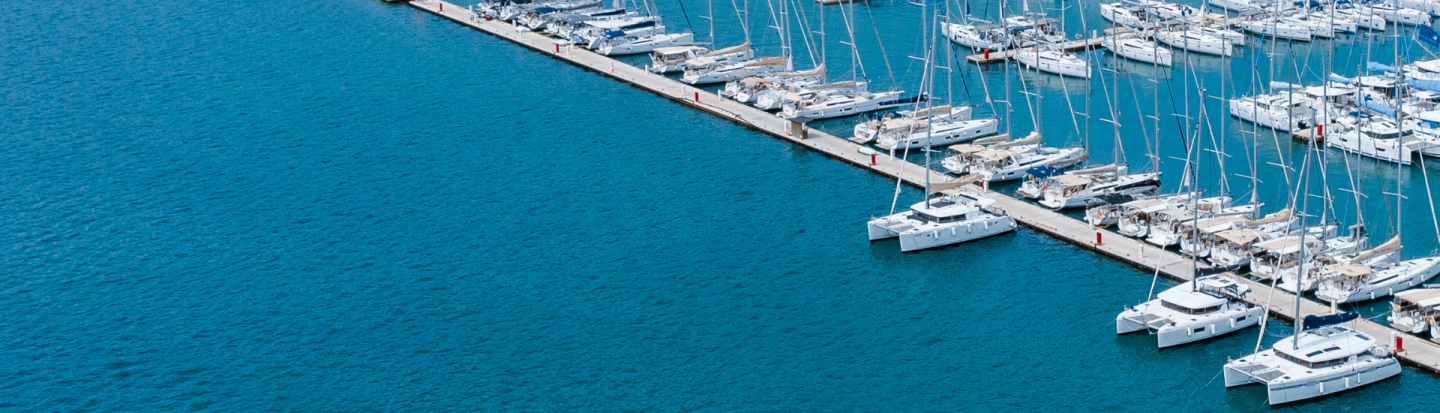 A drone view of a huge marina filled with sailing yachts and catamarans seen at a distance