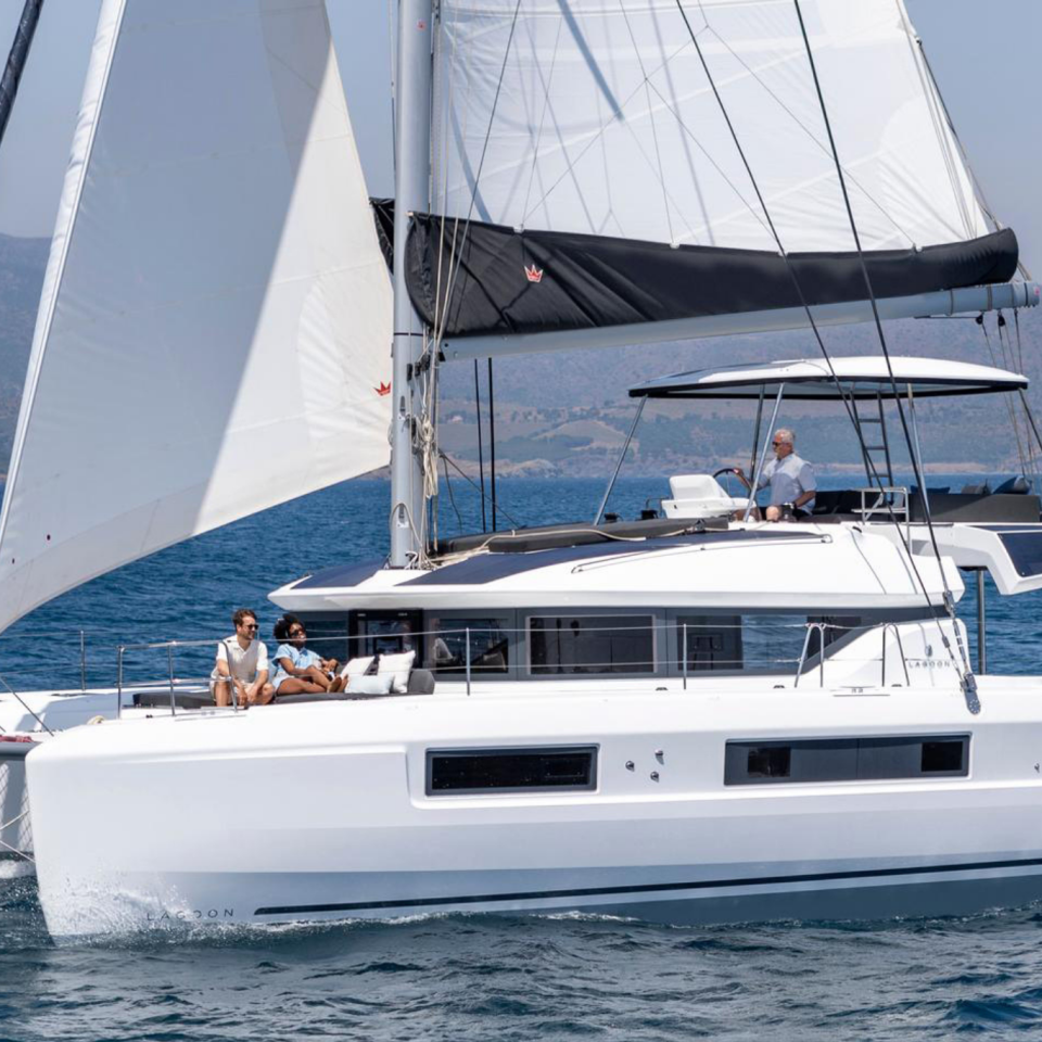 Lagoon 51 sailing with a man at the helm and guests enjoying the foredeck