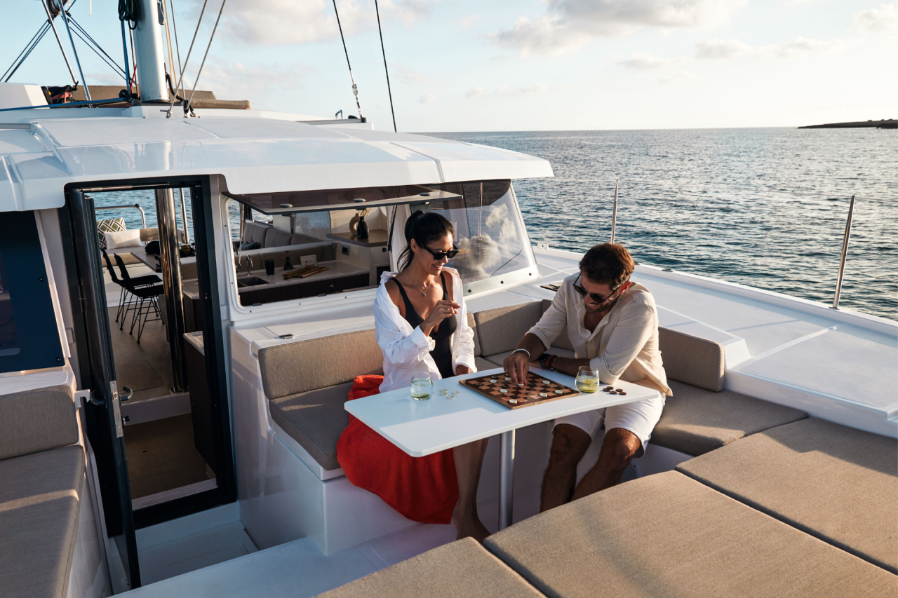 A man and a woman playing chess in the forward cockpit of a Bali sailing catamaran