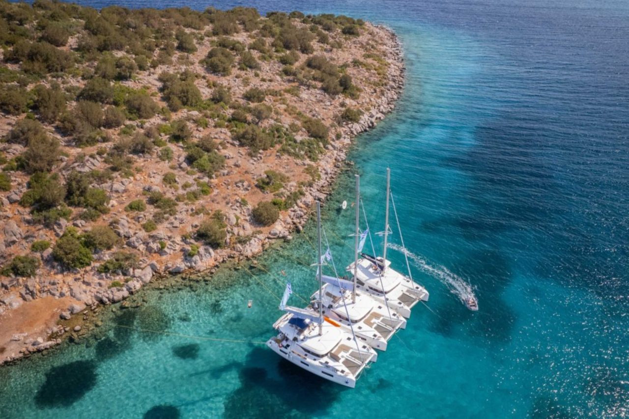 Distant view of three catamarans anchored side by side in Greece