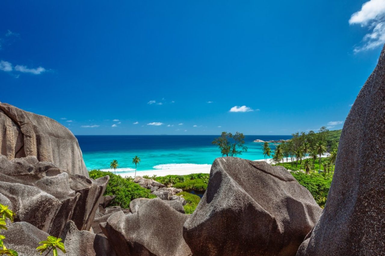 Granite rocks in the foreground and a white sand beach in the background in the Seychelles