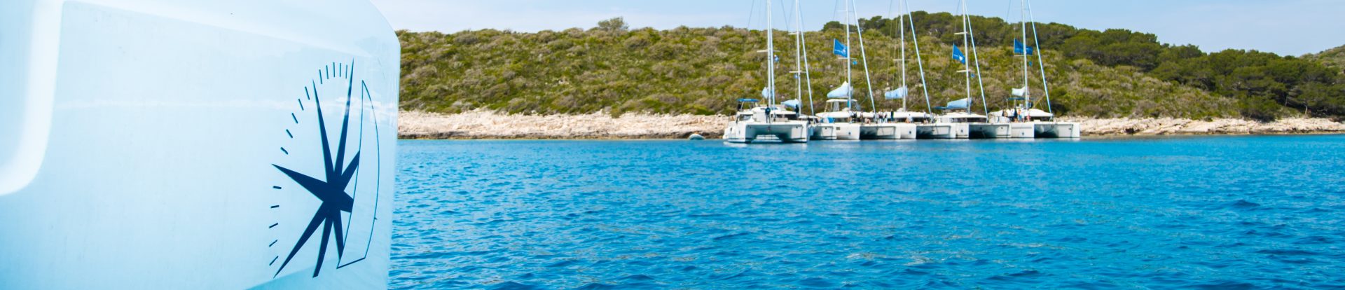 Lagoon sailing catamaran hull with a Navigare logo and several catamarans moored together in the distance