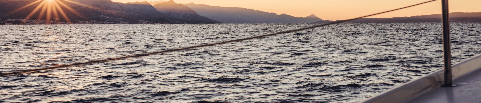 A sunset view over the mountains with the sea in the foreground