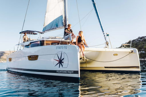 A young man and woman on the forward sundeck on a sailing catamaran at anchor
